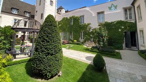 Un patio con una torre, un edificio cubierto de hiedra y una estatua.