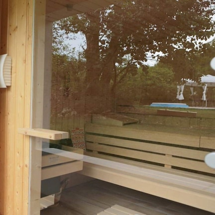 A wooden deck with a glass door leading to a room with a brick wall and a white robe hanging on the wall.