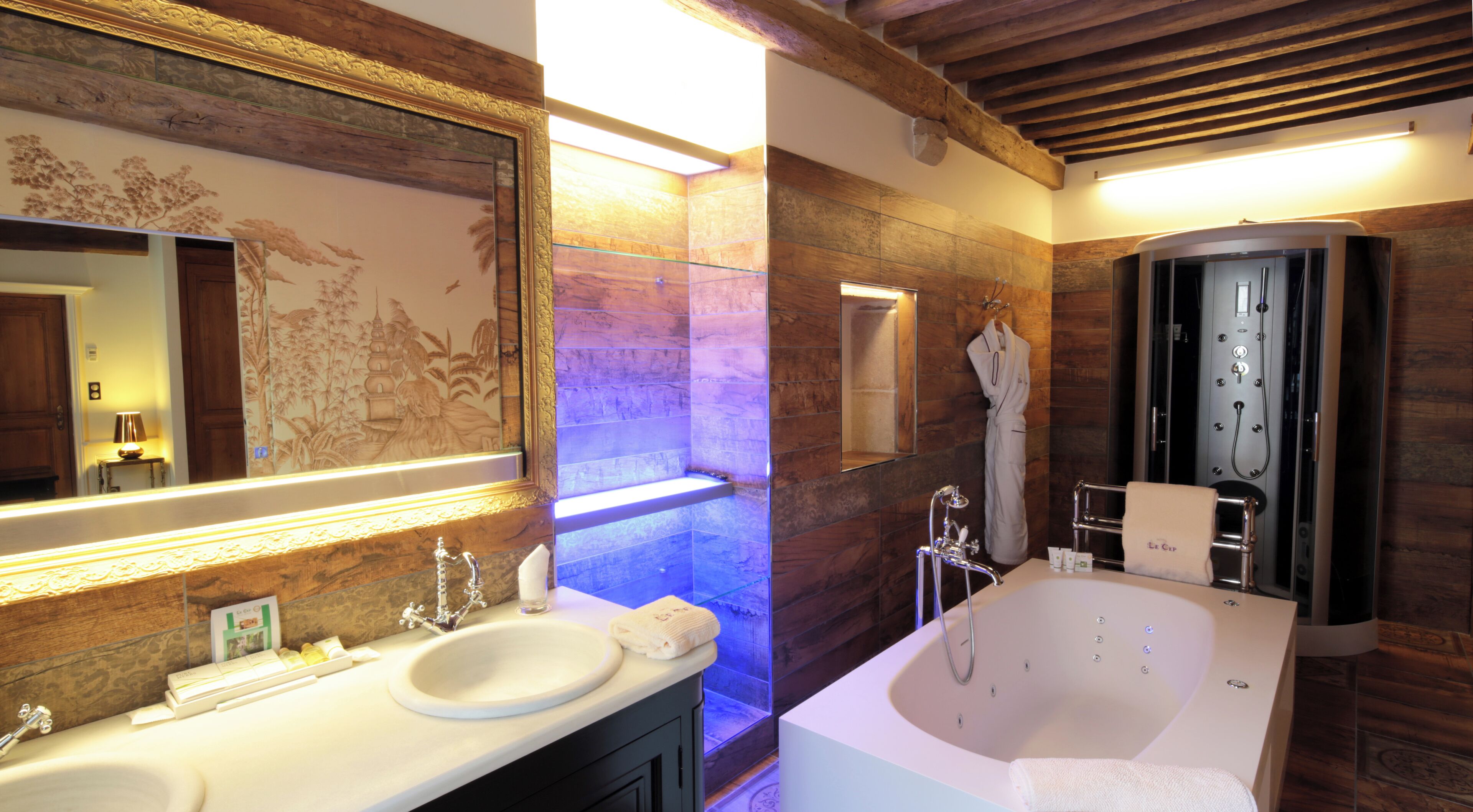Un baño con un espejo grande, dos lavamanos, una bañera y una ducha.