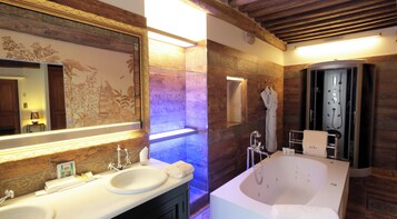 Un baño con un espejo grande, dos lavamanos, una bañera y una ducha.