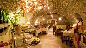 Un interior con paredes de piedra, un bufé con comida y bebidas, y un comedor con mesas y sillas.