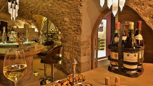 Una sala de degustación de vinos con pared de piedra, barra de madera y botellas de vino.