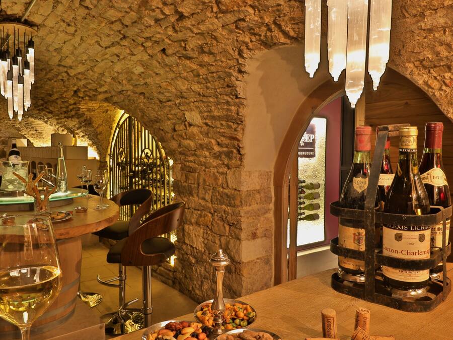 Una sala de degustación de vinos con pared de piedra, barra de madera y botellas de vino.