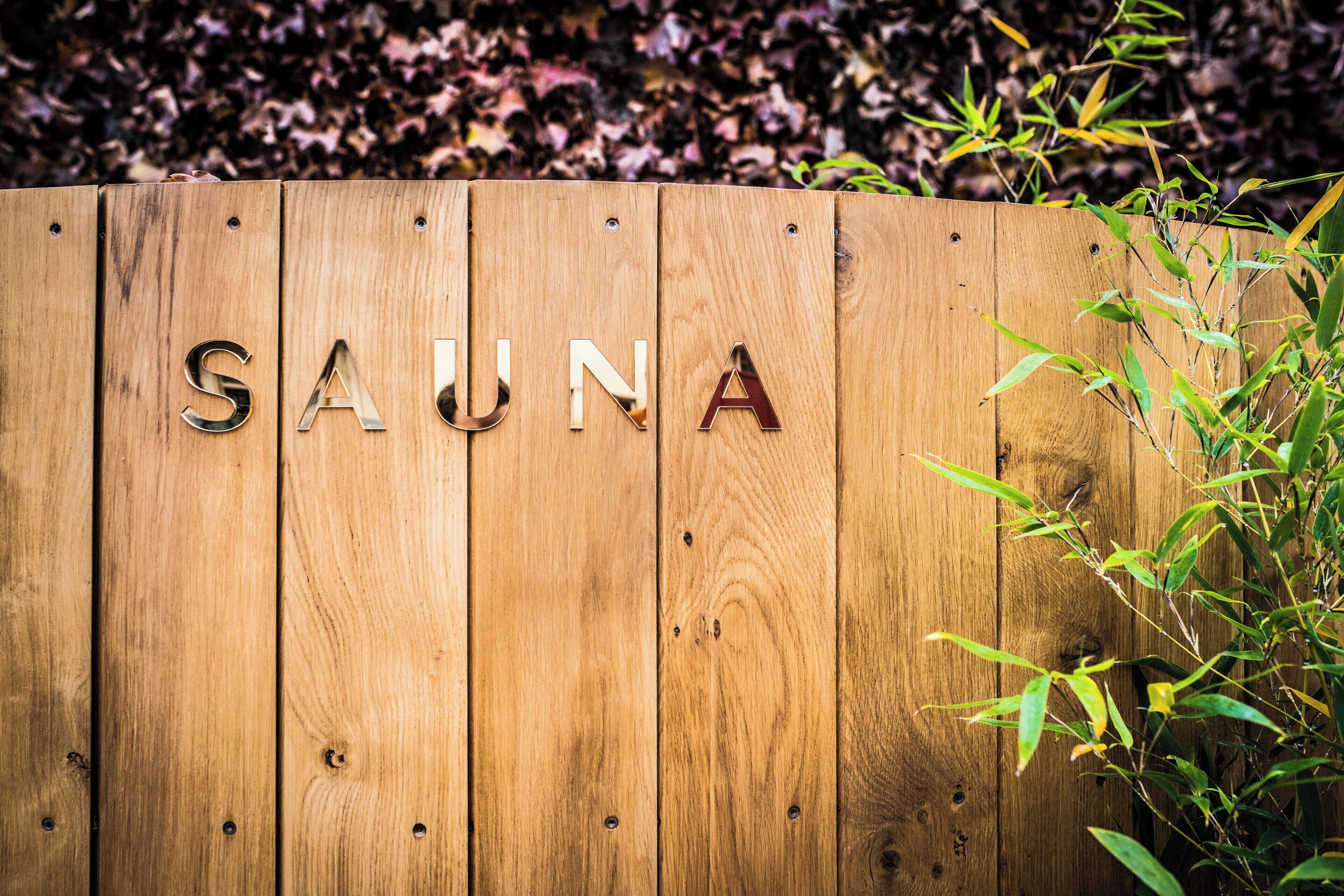 Un letrero de madera con la palabra 'SAUNA' escrita en letras de metal.