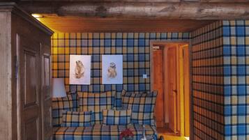 A cozy room with a plaid-patterned sofa, a yellow armchair, and wooden walls.