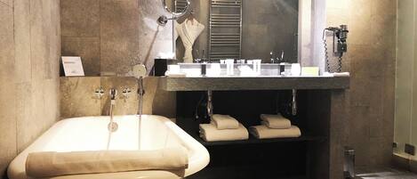 A modern bathroom with a freestanding bathtub, a large mirror, and a vanity with a sink and towel rack.