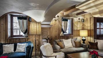 Un interior acogedor de cabaña de troncos, con un sofá, un sillón y una mesa de centro de madera.