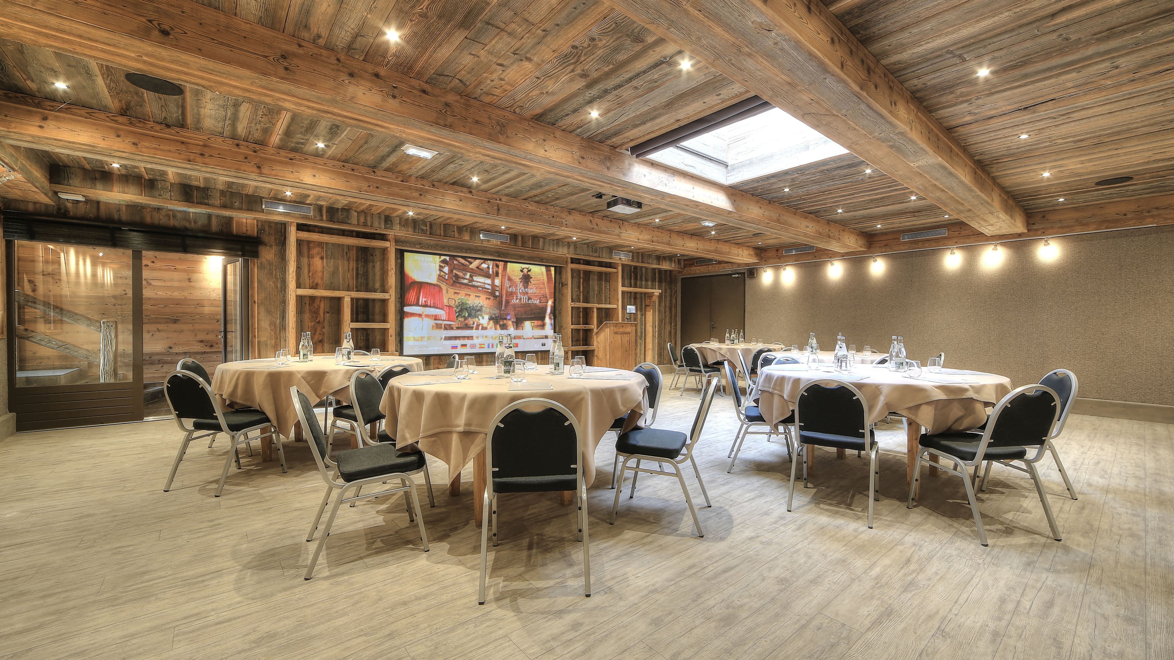 A conference room with round tables, chairs, and a wooden ceiling.