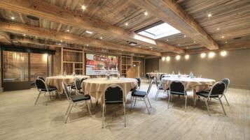 A conference room with round tables, chairs, and a wooden ceiling.