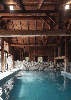 Un interior de madera con una pared de piedra y una piscina.