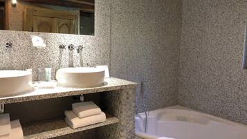A bathroom with two white sinks, a large mirror, and a freestanding bathtub.