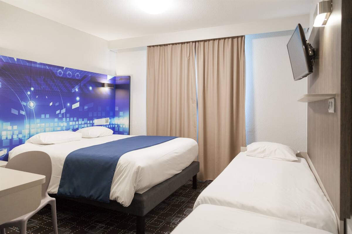 Ein Hotelzimmer mit Bett, Schreibtisch und einem an der Wand befestigten Fernseher.