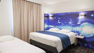 Une chambre d’hôtel avec un lit, une table de chevet et un mur orné d’un motif représentant un circuit imprimé bleu.