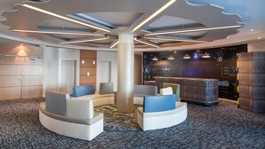 Eine moderne Lobby mit einer zentralen Säule, einer Sitzgelegenheit und einem Empfangsbereich.