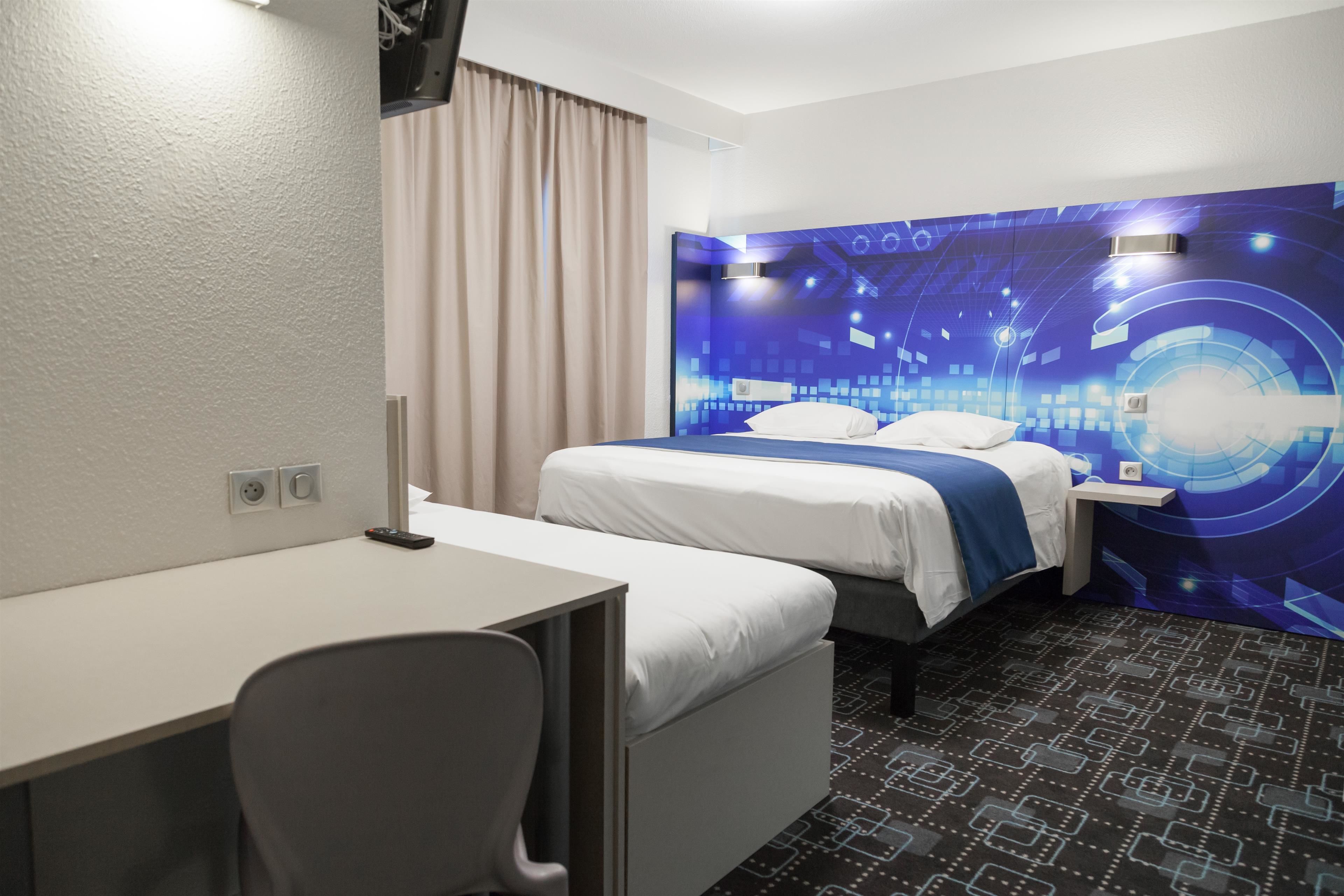 A hotel room with a bed, a desk, and a chair.