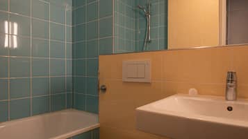 A bathroom with blue and beige tiles, a bathtub, a sink, and a shower.