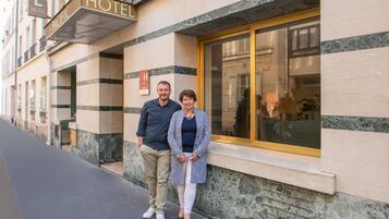 Exterior de un hotel con un cartel llamativo que dice 'HOTEL', un ventanal grande y una fachada de mármol.