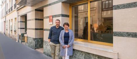 Exterior de un hotel con un cartel llamativo que dice 'HOTEL', un ventanal grande y una fachada de mármol.