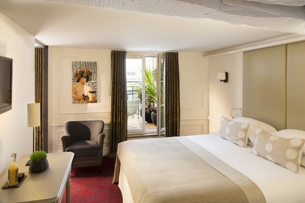 Une chambre d’hôtel avec un lit, un bureau doté d’une lampe, une chaise, une plante en pot et un tableau accroché au mur.