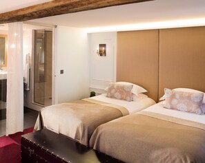 Une chambre d’hôtel avec deux lits, un plafond en bois, une douche en verre et une moquette rouge.
