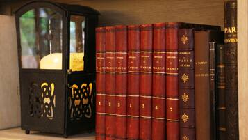 Une étagère sur laquelle sont alignés, par ordre numérique, des livres rouges portant le titre « Histoire de France », ainsi qu’une lanterne noire dotée d’un abat-jour en verre.