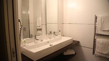 A modern bathroom with a large white sink, a mirror, and a towel rack.