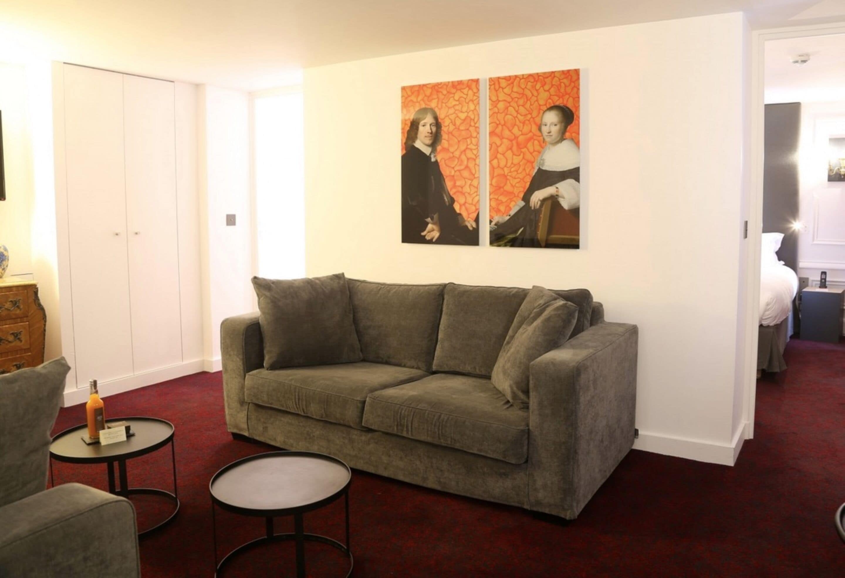 A living room with a grey sofa, two round tables, and a red carpet.