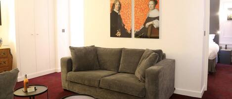 A living room with a grey sofa, two round tables, and a red carpet.