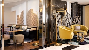 A modern interior with a sofa set, yellow armchairs, and a glass partition. - Hotel Victor Hugo Paris Kléber (Paris)