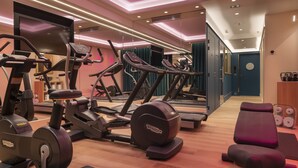 A modern gym with cardio machines, weight benches, and a mirror wall. - Hotel Victor Hugo Paris Kléber (Paris)