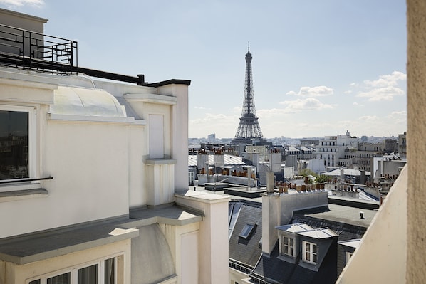 Vista de la Torre Eiffel desde un lugar elevado, con vistas a un paisaje urbano con diversos edificios y tejados.