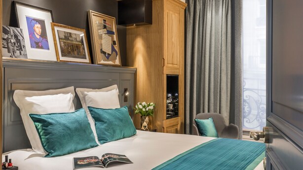 Une chambre d’hôtel avec un grand lit, une armoire en bois, une télévision et une fenêtre avec des rideaux.