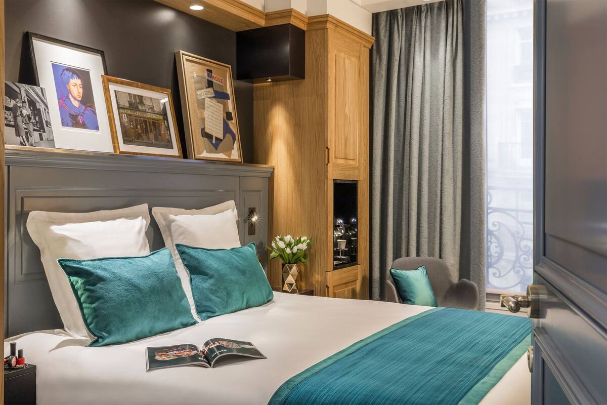 Une chambre d’hôtel avec un grand lit, une armoire en bois, une télévision et une fenêtre avec des rideaux.