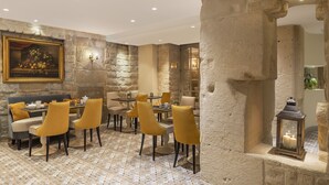 Un espace repas avec des murs en pierre, un tableau et une lanterne.