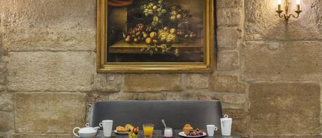 A dining table with a painting above it, a bench, and a wall-mounted light fixture.