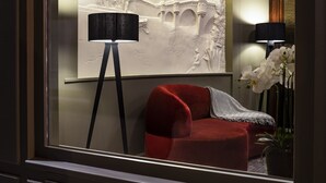 Une pièce avec un canapé rouge, un lampadaire et un mur orné d’une sculpture en relief.
