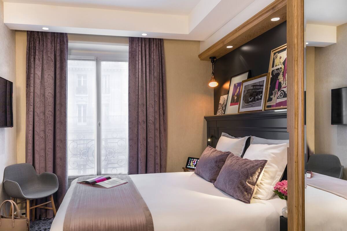 Une chambre d’hôtel avec un grand lit, un bureau, une chaise et une fenêtre avec des rideaux.