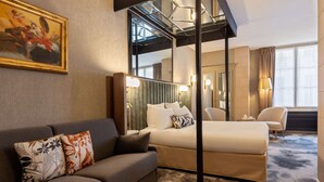 A hotel room with a sofa, a bed, a large mirror, and a window with curtains. - Best Western Saint Louis - Grand Paris Vincennes (Vincennes)