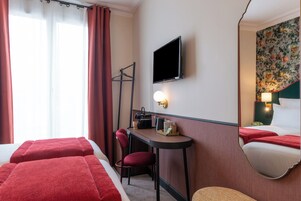 Una camera d'albergo con un letto, una scrivania, una sedia, una televisione e uno specchio.