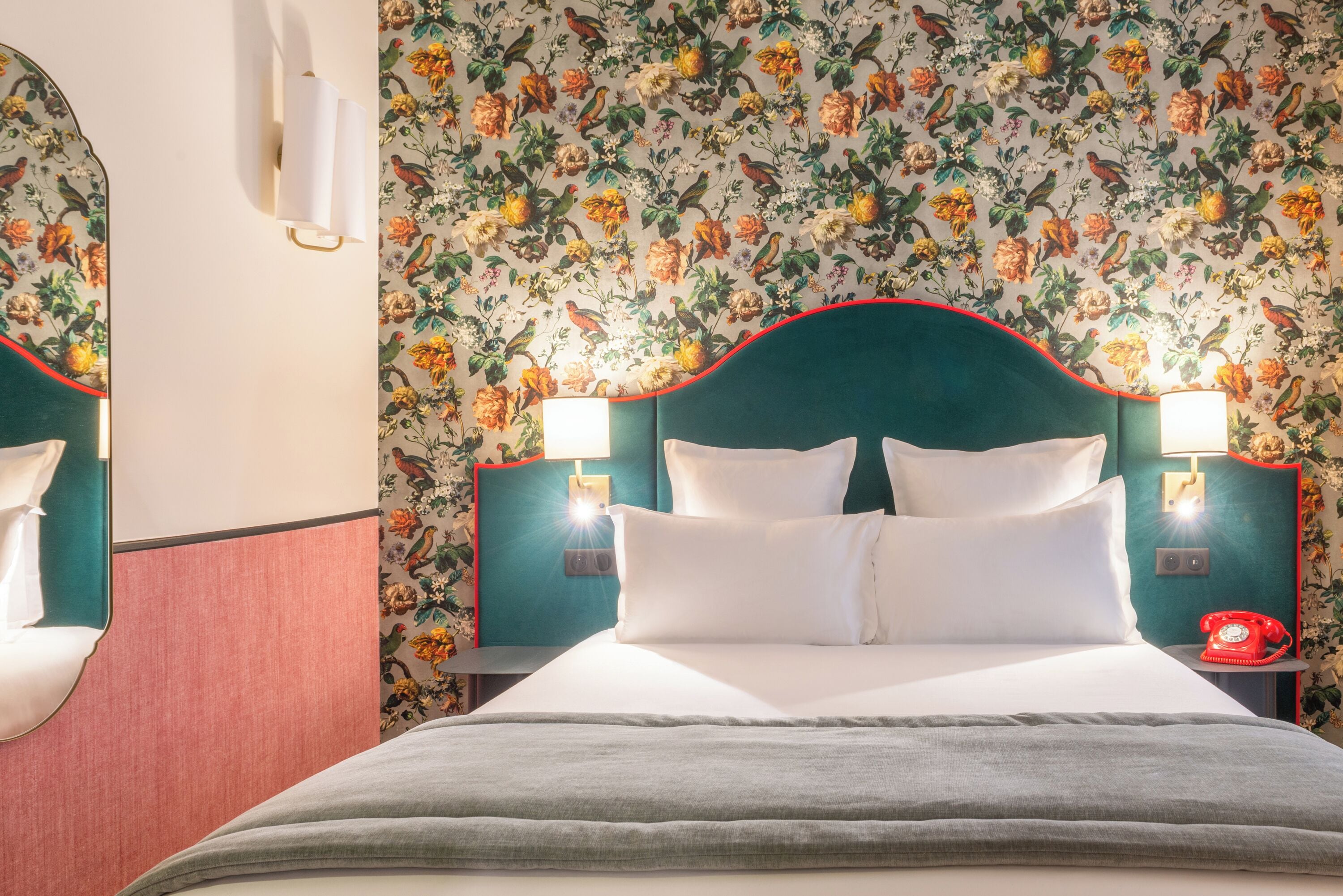 A neatly made bed with white linens, a teal headboard, and two bedside lamps.