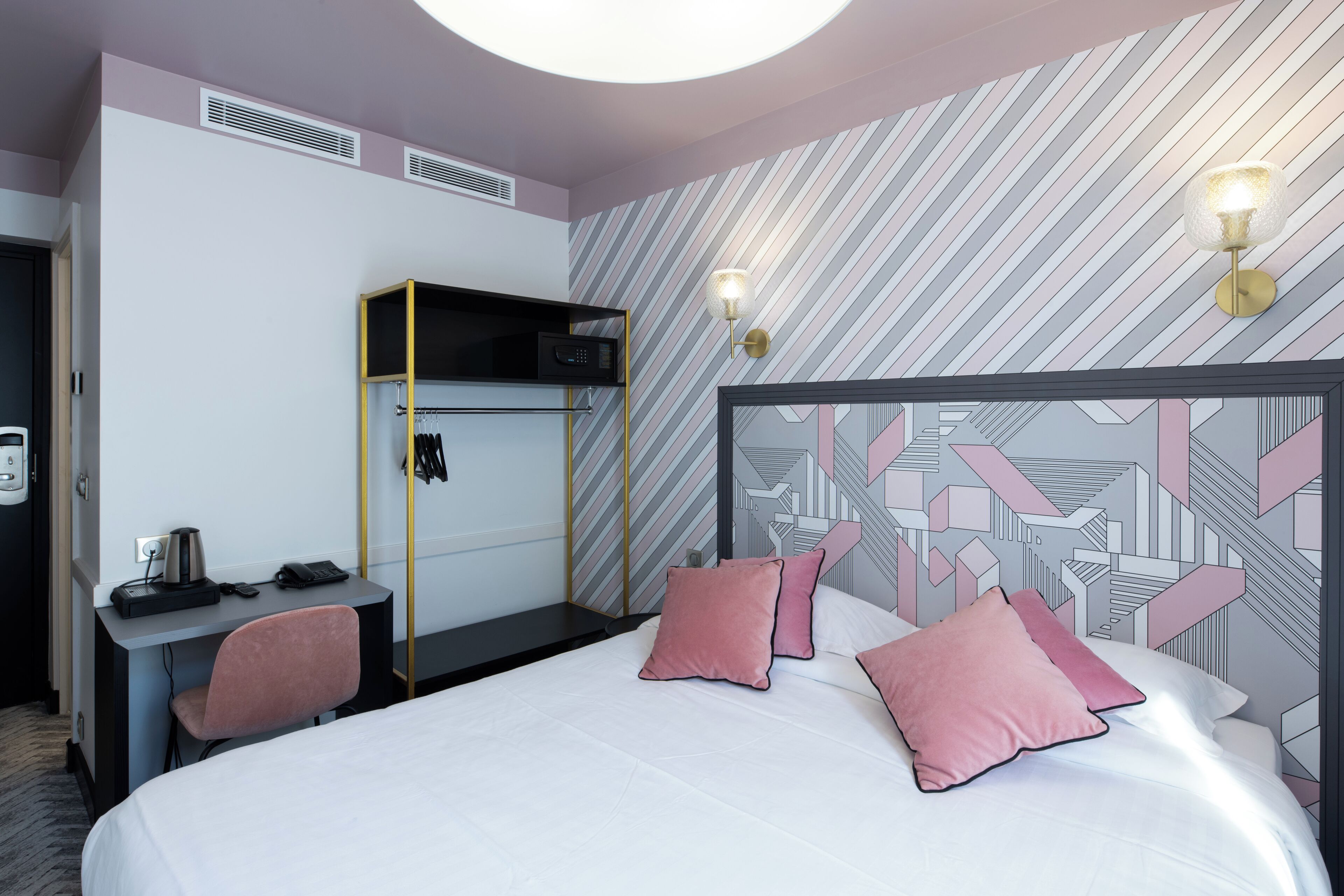 A hotel room with a bed, a desk, and a wardrobe.