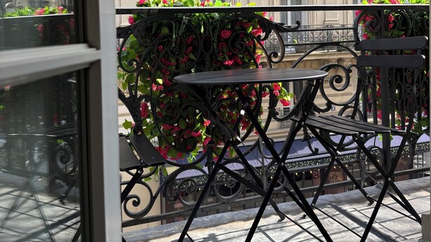 A balcony with a table and chairs, a view of a classical building with balconies, and a window with a view of the building. - Hotel Gérando (Paris)