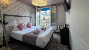 A hotel room with a bed, a TV, a balcony with a view of buildings, and a window with a view of the city. - Hotel Gérando (Paris)