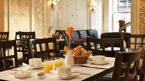 A dining area with a table set for breakfast, including croissants, orange juice, and coffee cups. - Hotel Gérando (Paris)