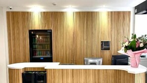 A reception desk with a wooden panel design, a refrigerator, and a small TV screen. - VLH Montparnasse Eiffel (Paris)