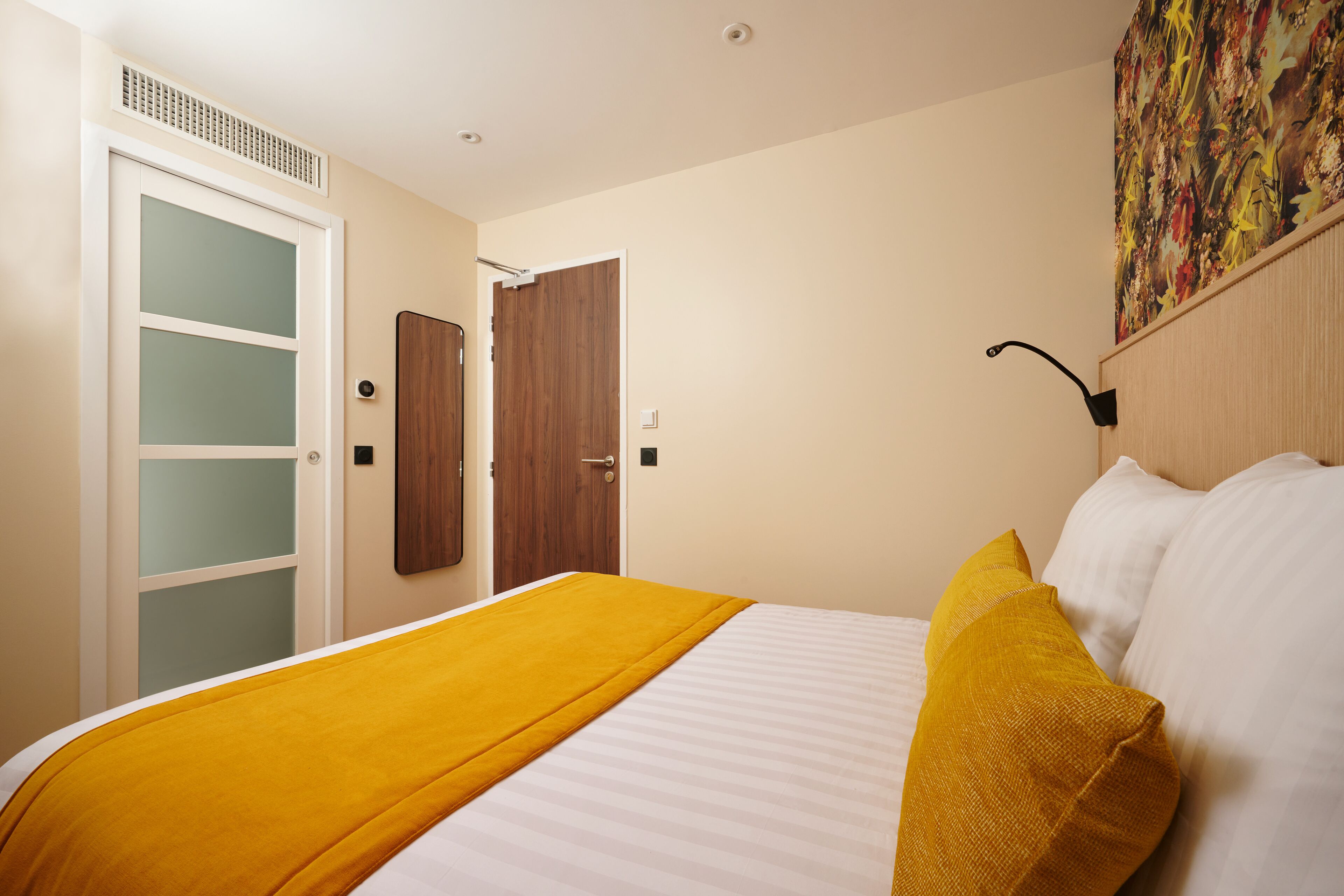 Una habitación de hotel con cama, puerta de madera y una obra de arte colgada en la pared.