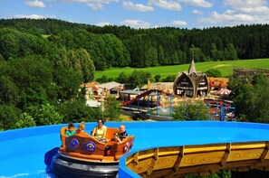 A water ride with a wooden boat and a building with a pointed roof in the background.