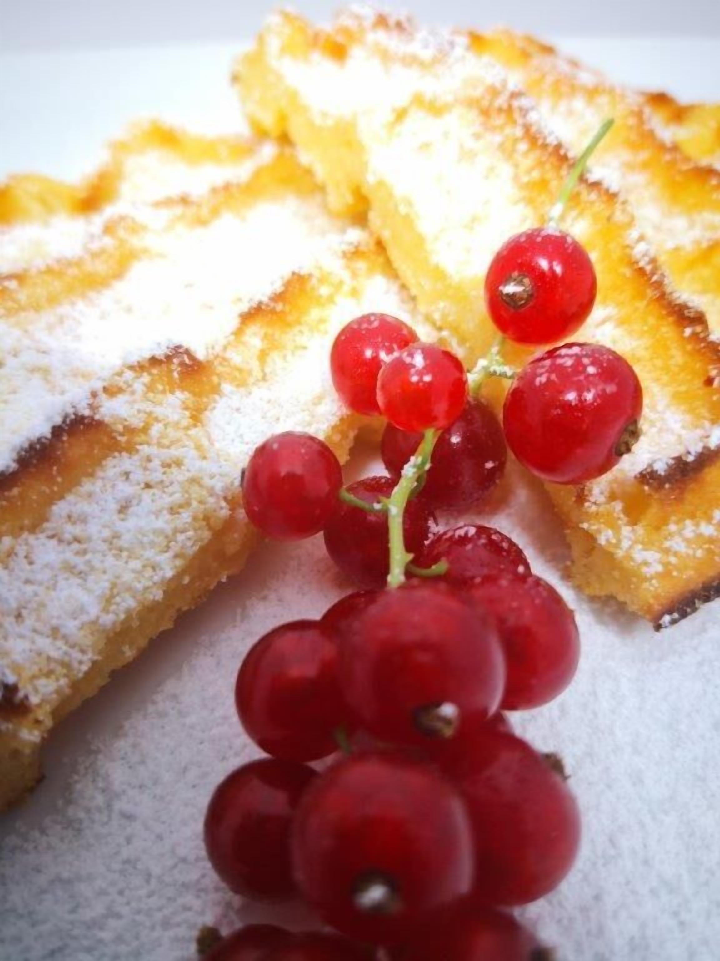 Ein Teller mit Kuchenstücken, bestäubt mit Puderzucker und mit Rote Trauben verziert.