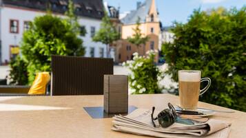 A table with a newspaper, a glass of beer, and a pair of glasses.