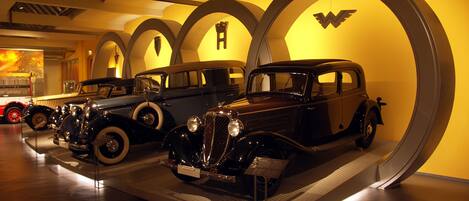 Vintage cars displayed in a museum with arched lighting.